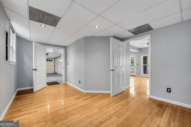 empty room featuring a paneled ceiling, ceiling fan, and light hardwood / wood-style floors