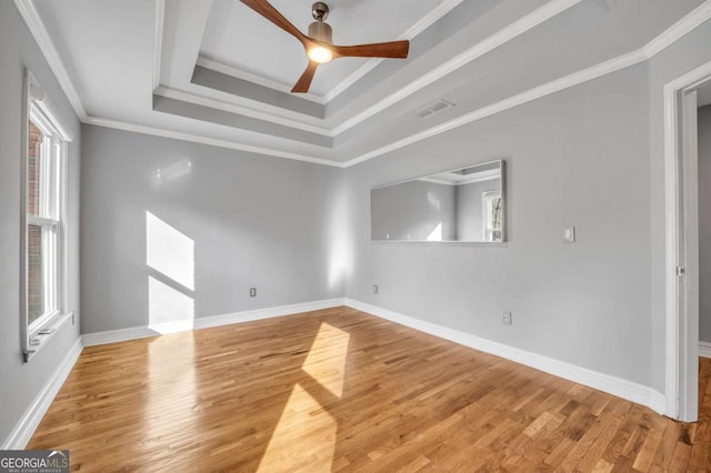 unfurnished room featuring a tray ceiling, ceiling fan, hardwood / wood-style flooring, and ornamental molding