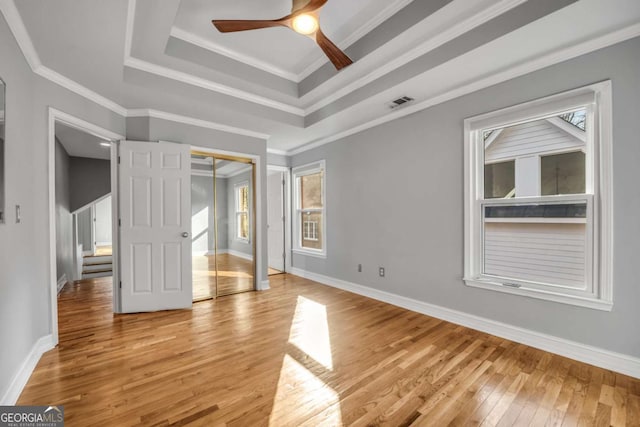 interior space with a wealth of natural light, ornamental molding, a tray ceiling, ceiling fan, and light hardwood / wood-style floors