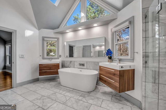 bathroom with vaulted ceiling with skylight, plenty of natural light, separate shower and tub, and vanity