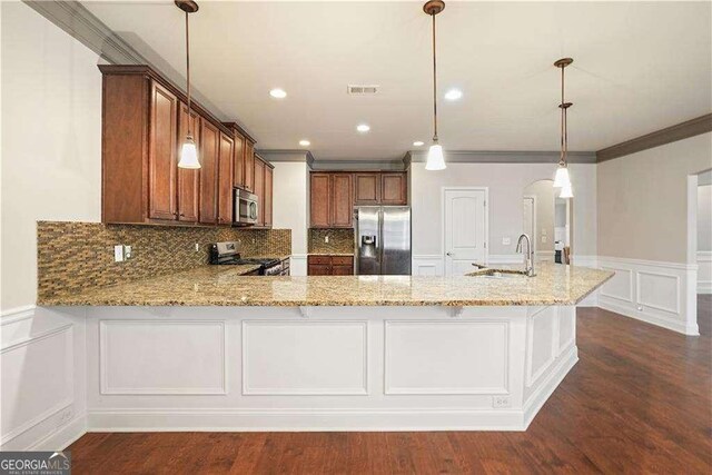 kitchen with sink, crown molding, decorative light fixtures, kitchen peninsula, and stainless steel appliances