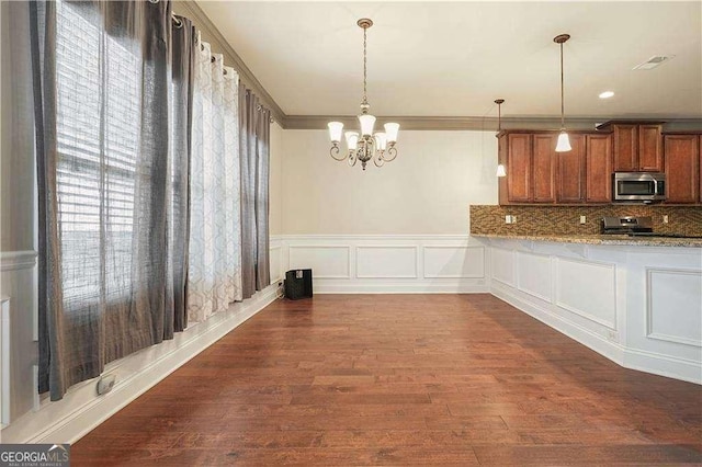 unfurnished dining area with dark hardwood / wood-style flooring, an inviting chandelier, and ornamental molding