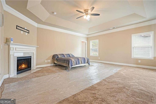 bedroom with light carpet, a tray ceiling, ceiling fan, and a high end fireplace