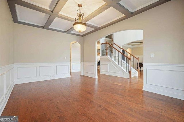 unfurnished room featuring hardwood / wood-style floors, crown molding, coffered ceiling, and beam ceiling