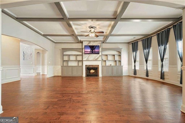 unfurnished living room with coffered ceiling, ceiling fan, built in features, beamed ceiling, and hardwood / wood-style floors