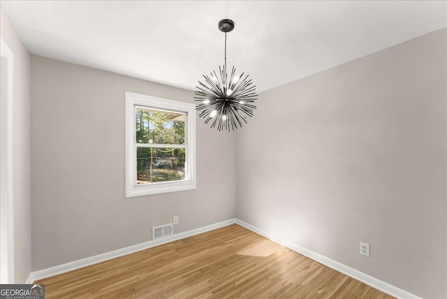 spare room with a chandelier and hardwood / wood-style floors