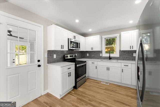 kitchen featuring sink, white cabinets, ceiling fan, light hardwood / wood-style floors, and stainless steel appliances