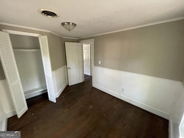 unfurnished bedroom featuring ornamental molding, a closet, and dark wood-type flooring