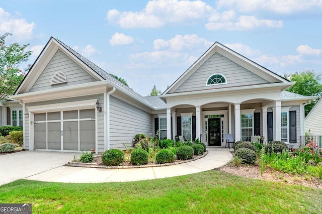 view of front of home featuring a front yard, a garage, and covered porch