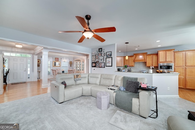 living room with ceiling fan, ornate columns, and light hardwood / wood-style flooring