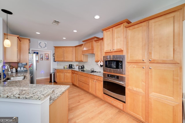 kitchen featuring sink, hanging light fixtures, light brown cabinetry, light hardwood / wood-style floors, and stainless steel appliances