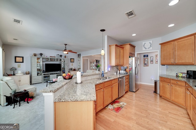 kitchen with ceiling fan, sink, kitchen peninsula, decorative light fixtures, and appliances with stainless steel finishes