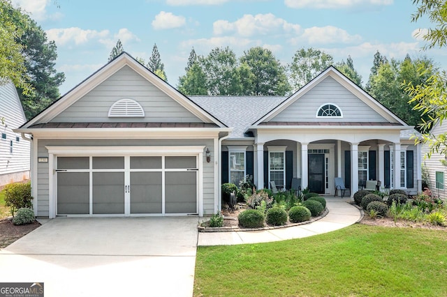 view of front of home featuring covered porch, a front yard, and a garage