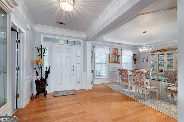 foyer with light wood-type flooring, crown molding, and a notable chandelier