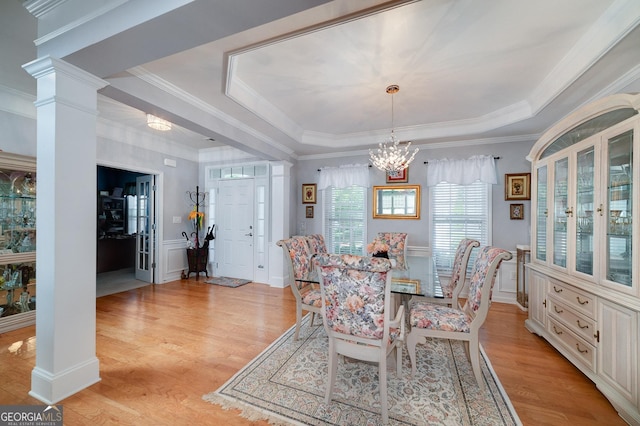 dining area with a tray ceiling, ornamental molding, and light wood-type flooring