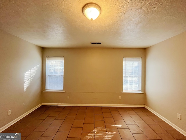 empty room with a textured ceiling and a wealth of natural light