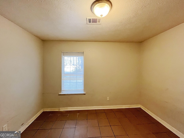 spare room featuring dark tile patterned floors