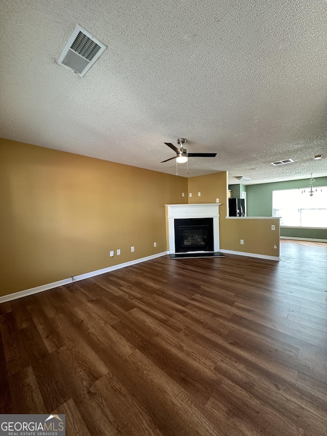 unfurnished living room featuring ceiling fan, dark hardwood / wood-style flooring, and a textured ceiling