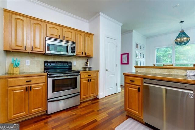 kitchen with hanging light fixtures, dark hardwood / wood-style floors, ornamental molding, stainless steel appliances, and a chandelier