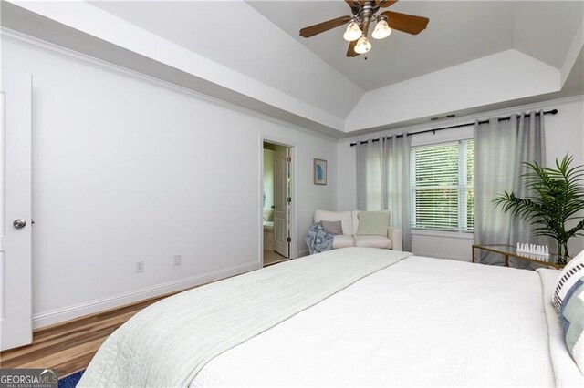 bedroom with ensuite bathroom, a tray ceiling, ceiling fan, wood-type flooring, and lofted ceiling