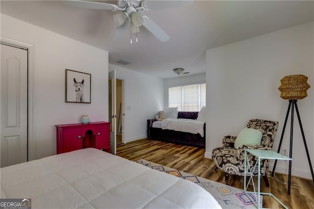 bedroom featuring baseboards, visible vents, wood finished floors, and a ceiling fan