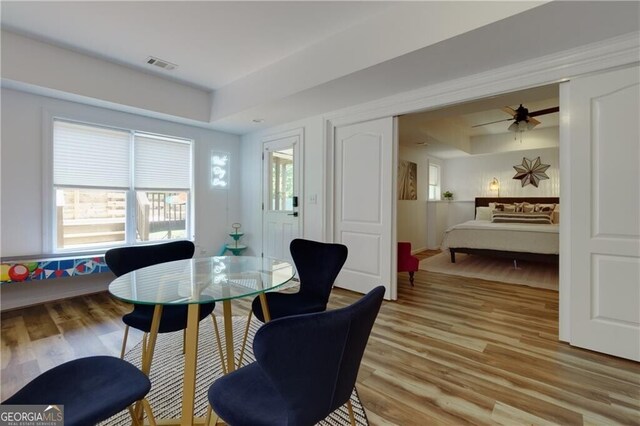 dining space with a tray ceiling, ceiling fan, and light hardwood / wood-style flooring