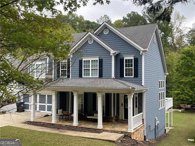 view of front of house with covered porch, a garage, and a front lawn