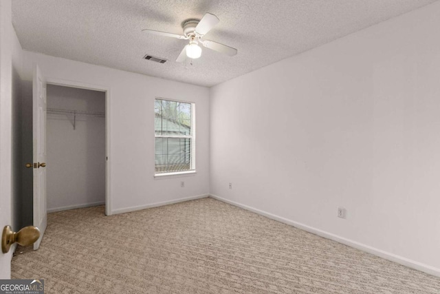 unfurnished bedroom featuring ceiling fan, a closet, light carpet, and a textured ceiling