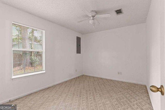 empty room with ceiling fan, light colored carpet, a textured ceiling, and electric panel