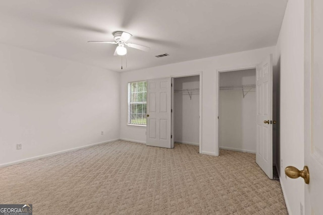 unfurnished bedroom featuring light carpet, two closets, and ceiling fan