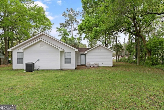 rear view of property with central AC unit and a yard