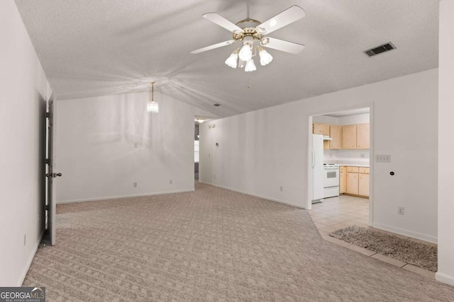 empty room featuring light carpet, a textured ceiling, ceiling fan, and lofted ceiling