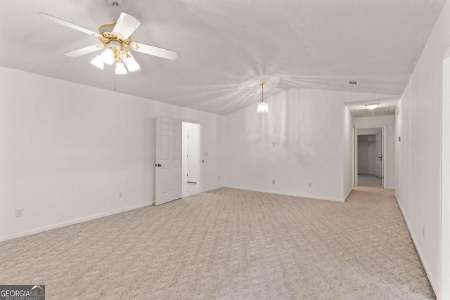 spare room with ceiling fan, a textured ceiling, light carpet, and vaulted ceiling