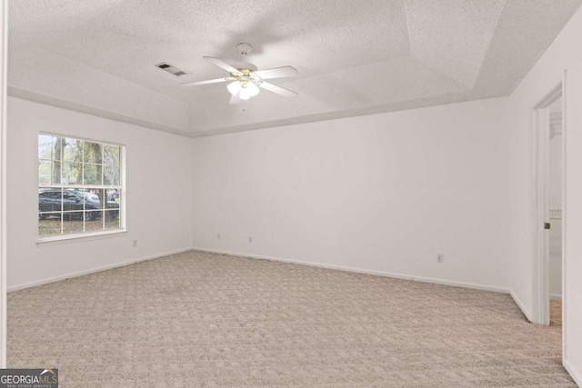 carpeted spare room with ceiling fan, a raised ceiling, and a textured ceiling