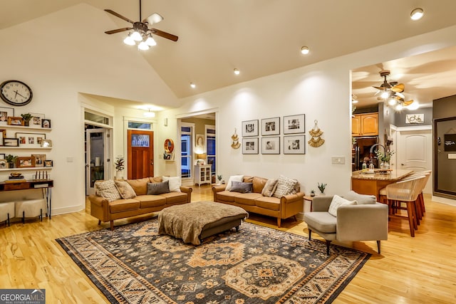 living room featuring high vaulted ceiling, light hardwood / wood-style floors, and ceiling fan