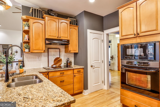 kitchen featuring sink, light stone counters, tasteful backsplash, light hardwood / wood-style floors, and black appliances