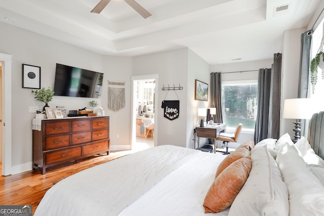 bedroom with light hardwood / wood-style floors, a raised ceiling, and ceiling fan