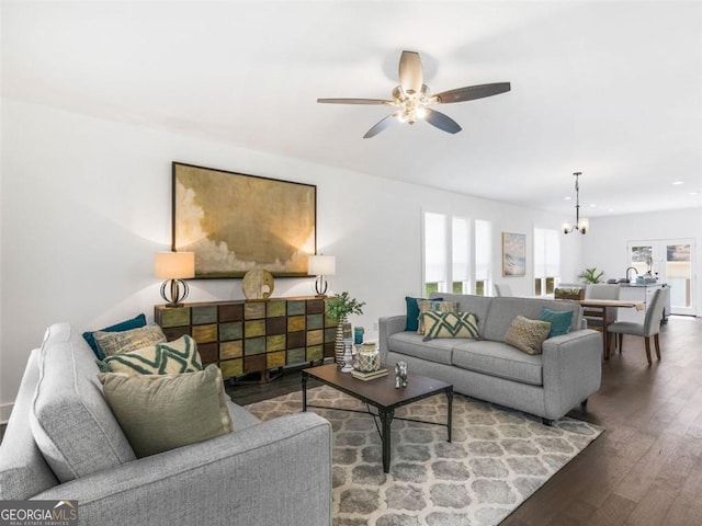 living room featuring ceiling fan with notable chandelier and hardwood / wood-style flooring