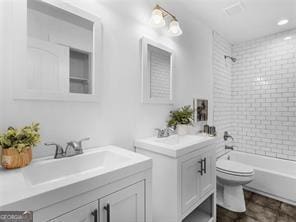 full bathroom with vanity, tiled shower / bath combo, and toilet