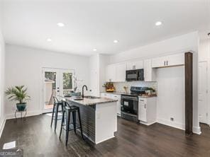 kitchen featuring french doors, electric range, white cabinetry, a breakfast bar area, and an island with sink