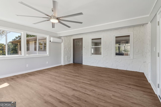 spare room with a wall unit AC, a healthy amount of sunlight, and hardwood / wood-style flooring