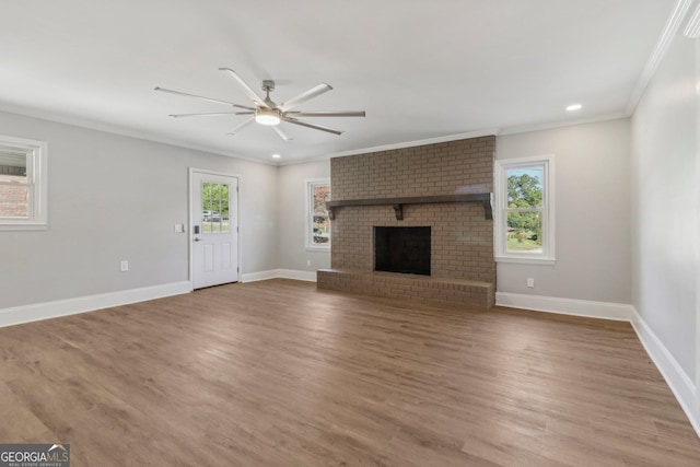 unfurnished living room featuring a brick fireplace, hardwood / wood-style flooring, ceiling fan, and ornamental molding