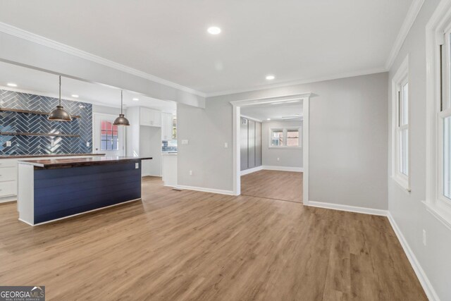 kitchen with light wood-type flooring, backsplash, white cabinets, hanging light fixtures, and butcher block counters