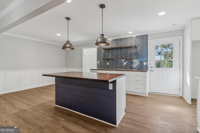 kitchen featuring wood counters, crown molding, white cabinets, hardwood / wood-style floors, and hanging light fixtures