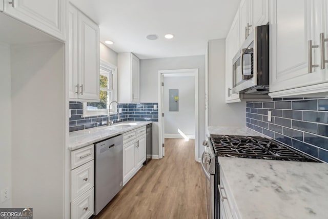 kitchen featuring white cabinetry, light hardwood / wood-style flooring, light stone countertops, and appliances with stainless steel finishes