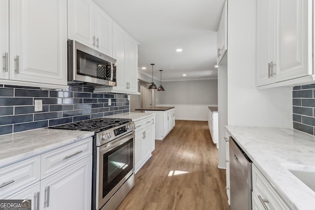 kitchen with light stone countertops, stainless steel appliances, white cabinetry, and light hardwood / wood-style floors