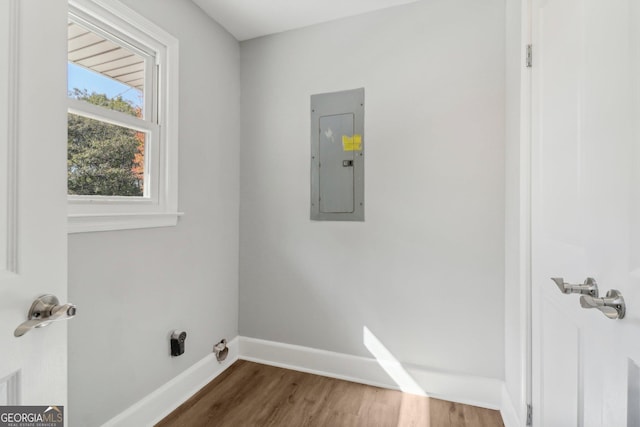 clothes washing area with electric panel and hardwood / wood-style flooring