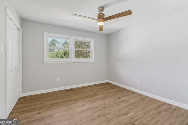 unfurnished bedroom with hardwood / wood-style floors, ceiling fan, and a closet