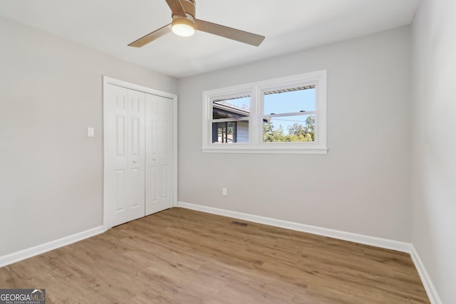 unfurnished bedroom with ceiling fan, light hardwood / wood-style flooring, and a closet