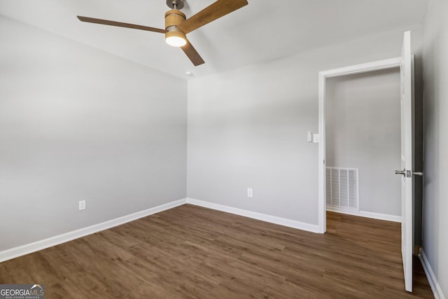 empty room with ceiling fan and dark hardwood / wood-style flooring